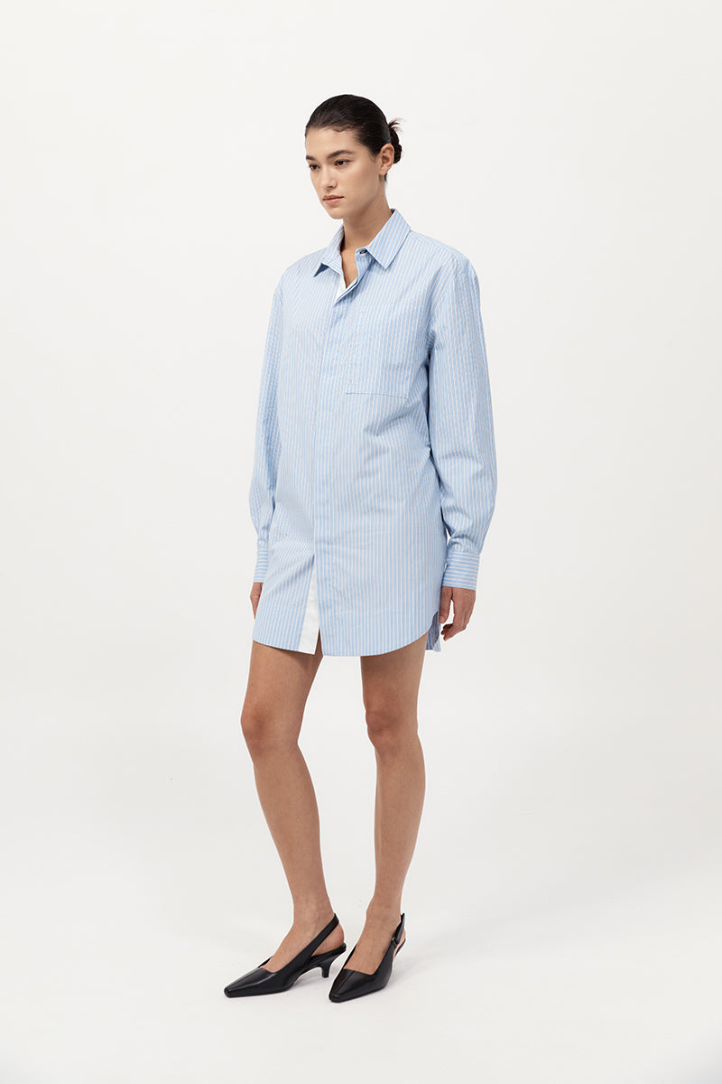 Woman wearing an oversized shirt dress in light blue pinstripes paired with black kitten heels
