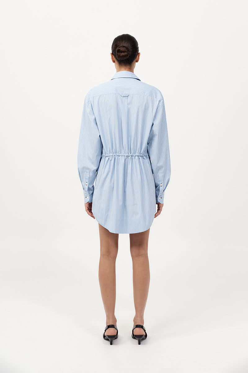 Woman wearing a light blue striped dress on a white background