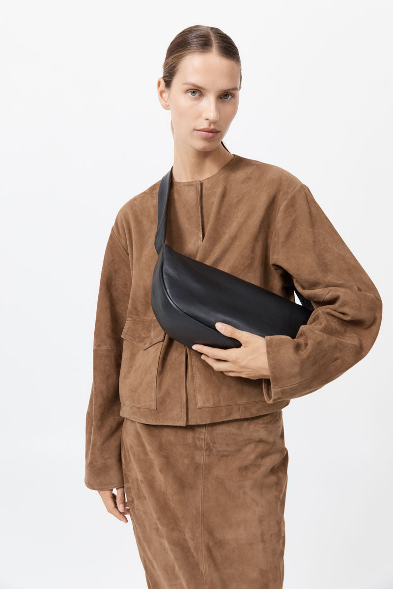 Woman holding a black bag wearing a brown outfit on a white background