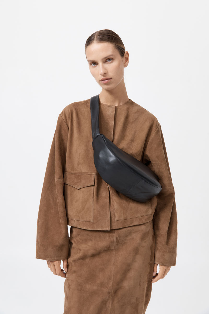 Person wearing a brown outfit with a black bag on a white background