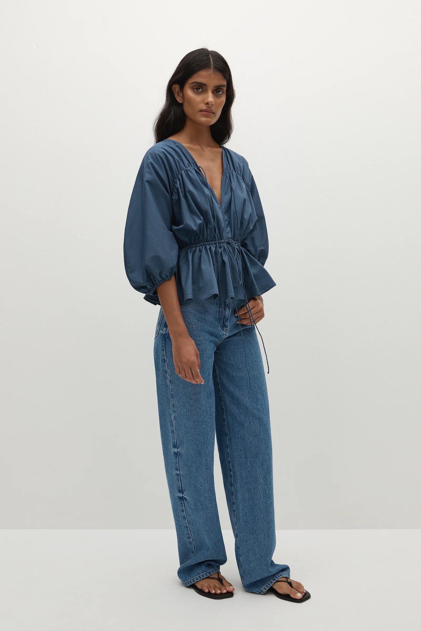 Woman wearing a romantic blue blouse paired with straight leg denim 
