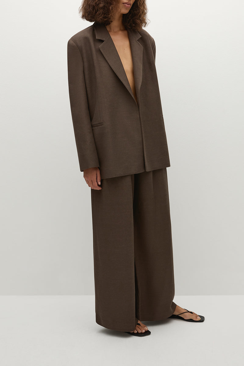 Woman wearing a brown linen suit on a white background