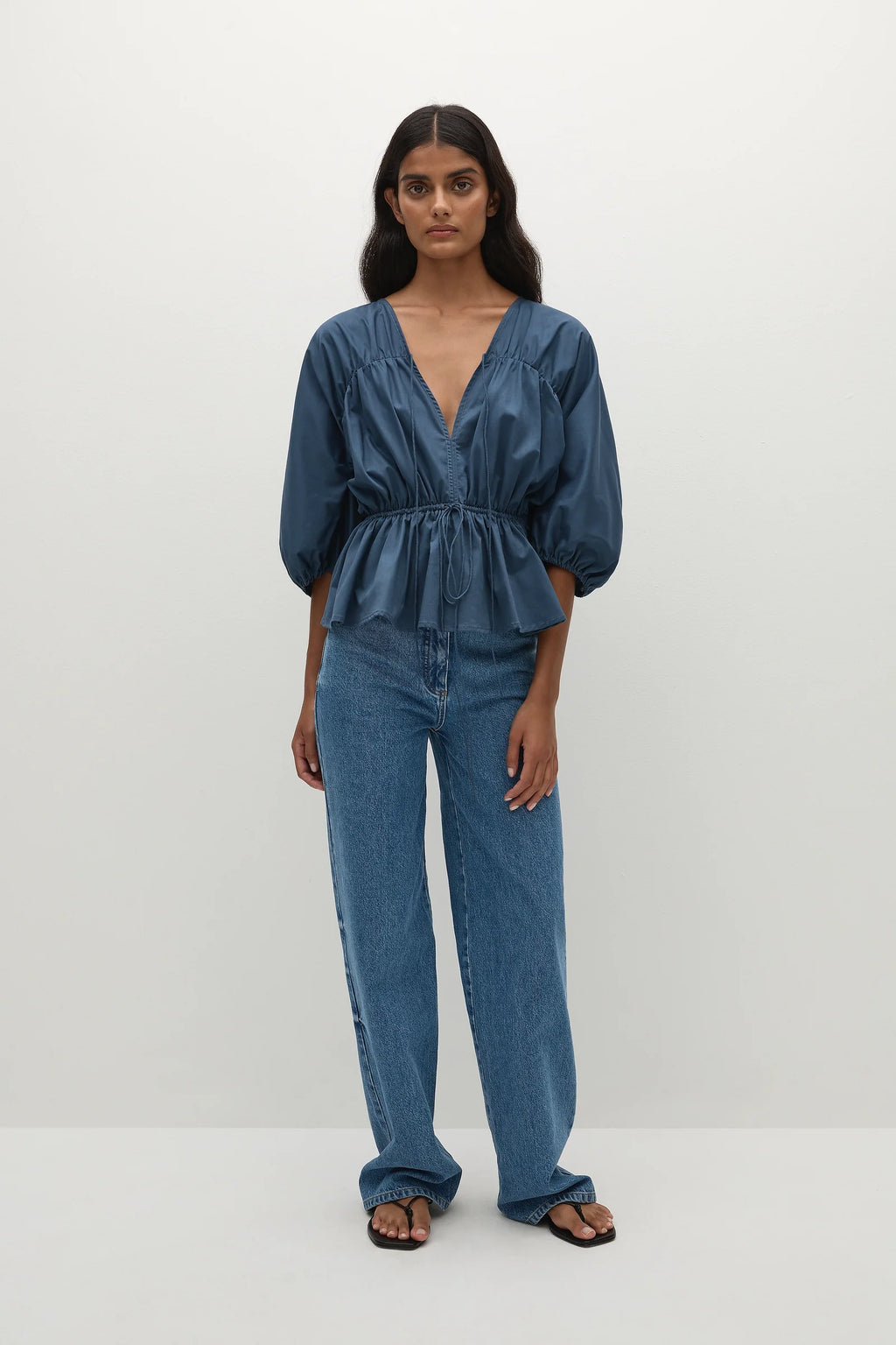 Woman wearing a vintage blue blouse with puff sleeves paired with denim jeanse
