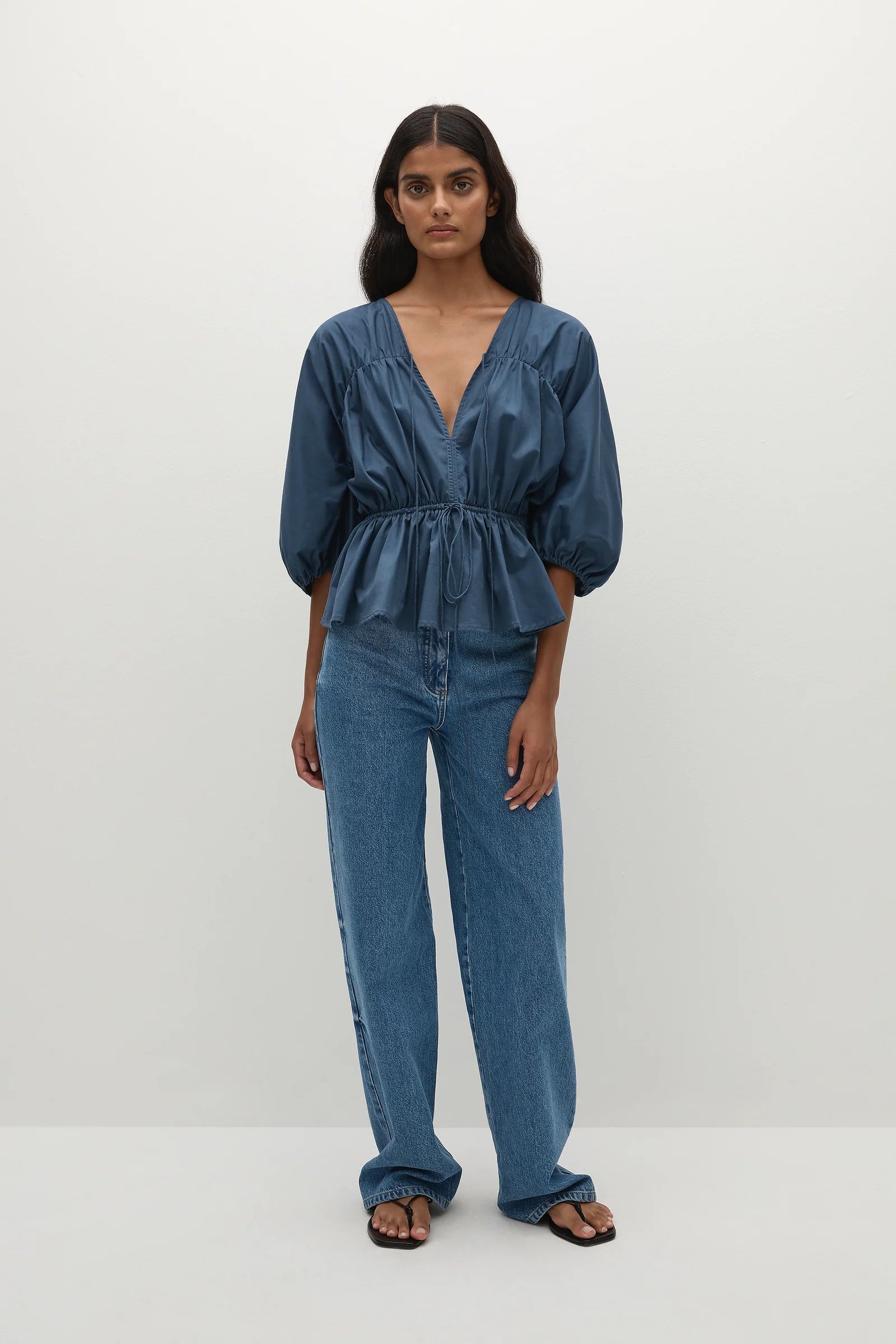 Woman wearing a vintage blue blouse with puff sleeves paired with denim jeanse