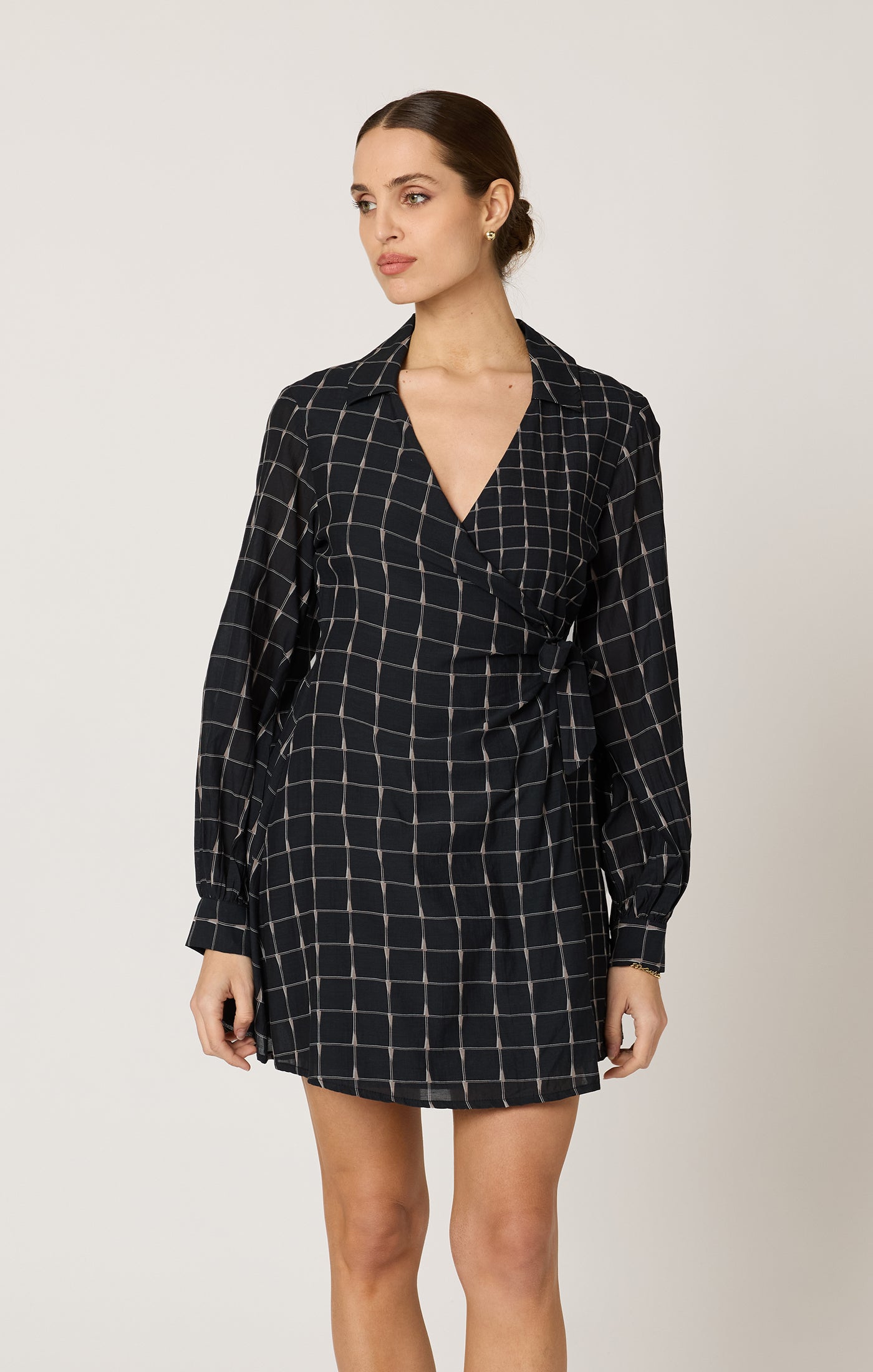 Woman wearing a black checkered dress against a plain background