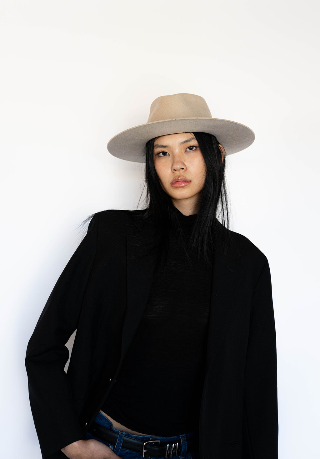 woman wearing a flat brim tan wool fedora paired with a black blazer